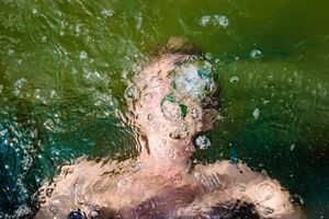 Underwater photo showing bubbles and motion blur in green-tinted water during swimming.