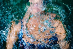 An abstract aerial photograph of turquoise ocean waters swirling with orange and peach colored patterns.