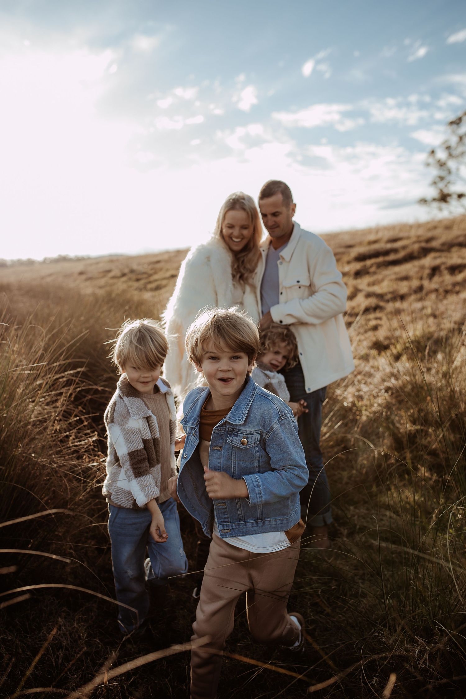 A family walks through golden grass fields during sunset.