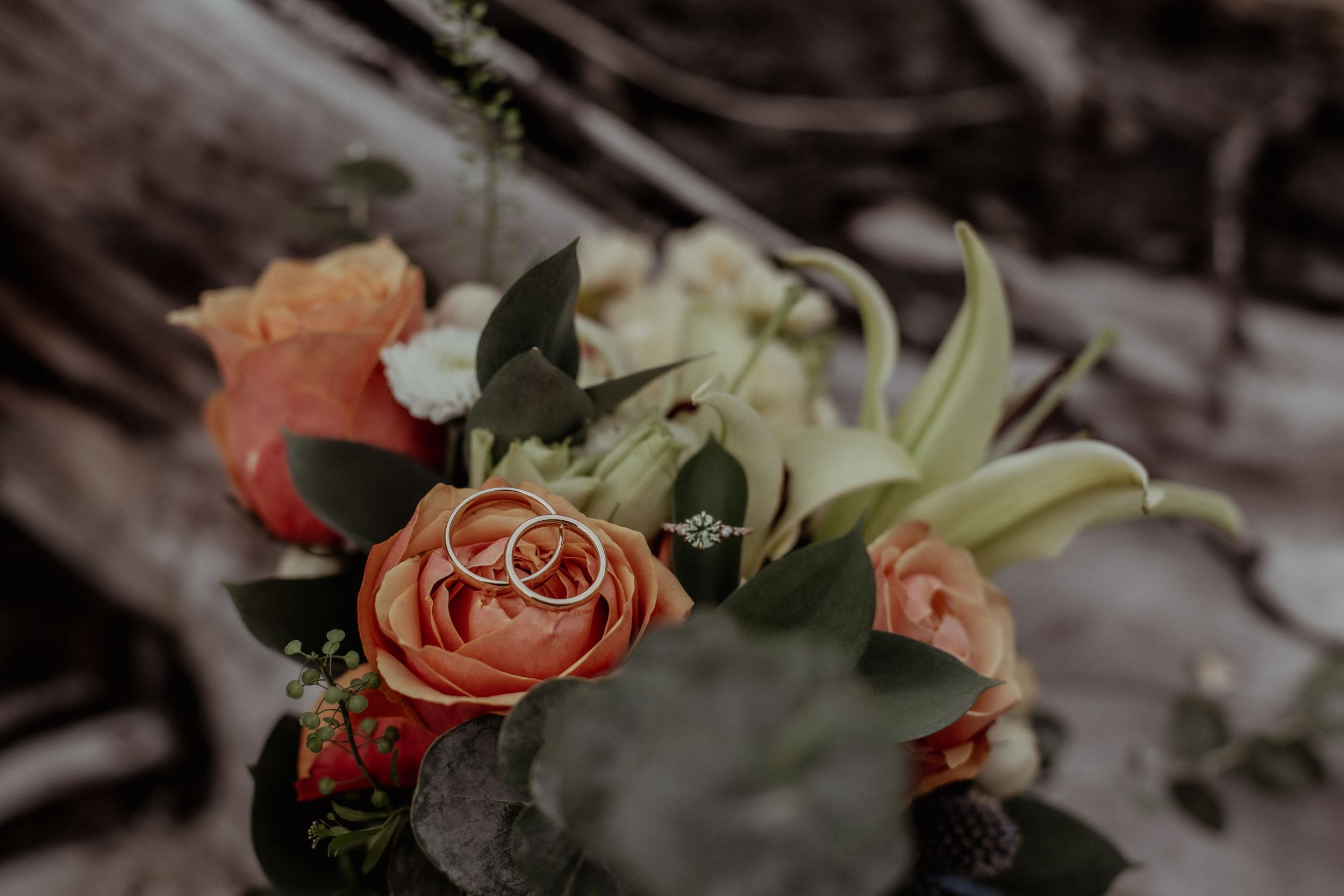 Delicate coral and peach roses with greenery arranged as wedding decorations.