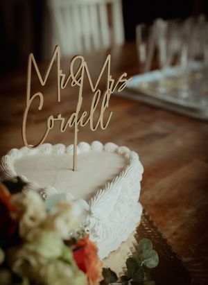 Elegant wedding decor details showing gold script signage and delicate white feathers with soft floral arrangements.
