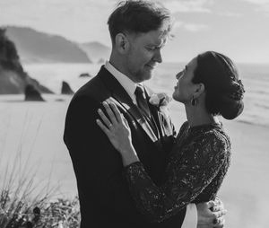 A romantic black and white photo series of a couple embracing on a scenic coastal cliff at sunset.