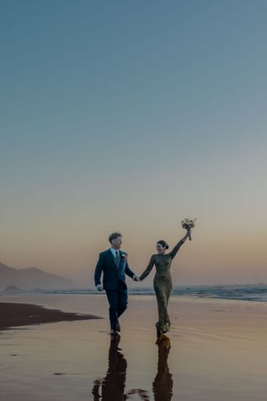 Silhouettes dancing on a vast beach at sunset with mountains in the distance.