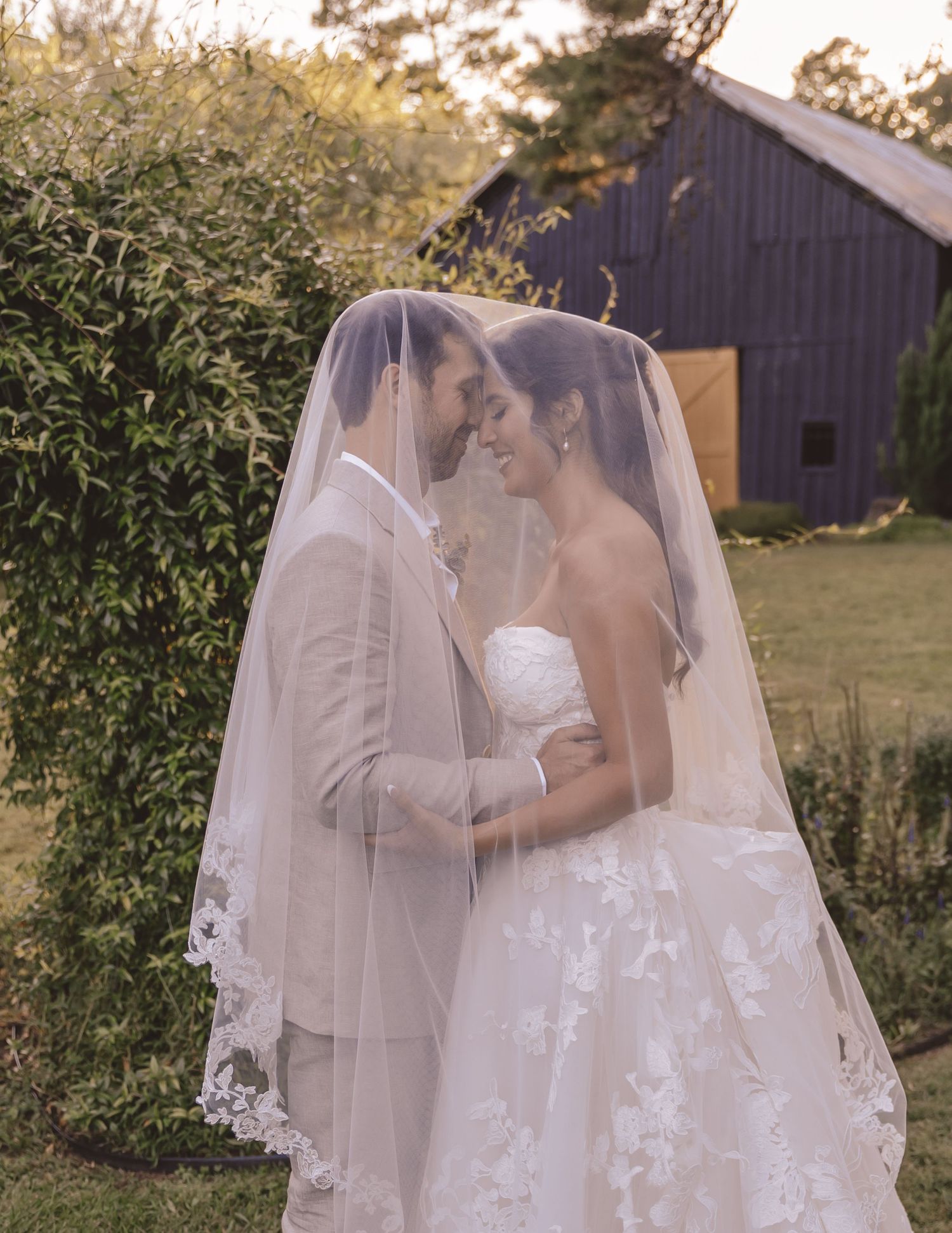 Bride and groom embracing under the wedding veil at Farmhouse Siloam in Mount Airy, NC