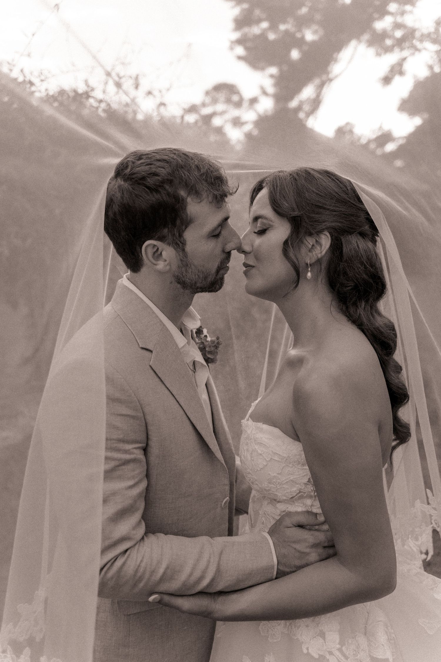 Bride and groom kissing under a veil at Farmhouse Siloam in Mount Airy, NC