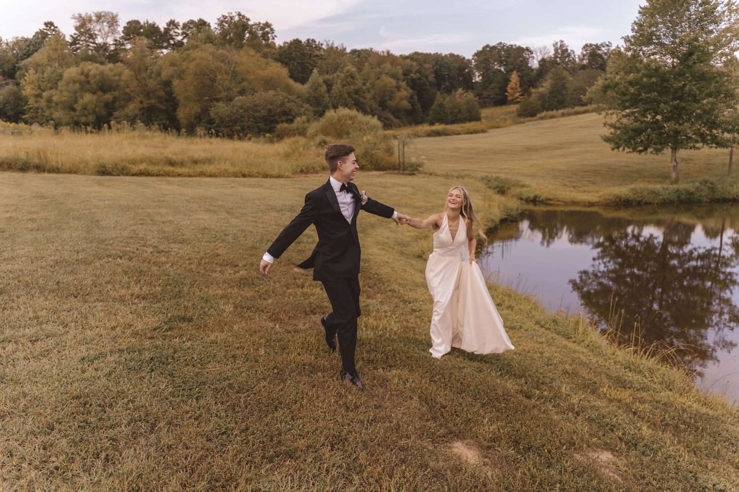 Bride and groom playfully running by the pond at Willow and Stone Events in Mocksville, NC