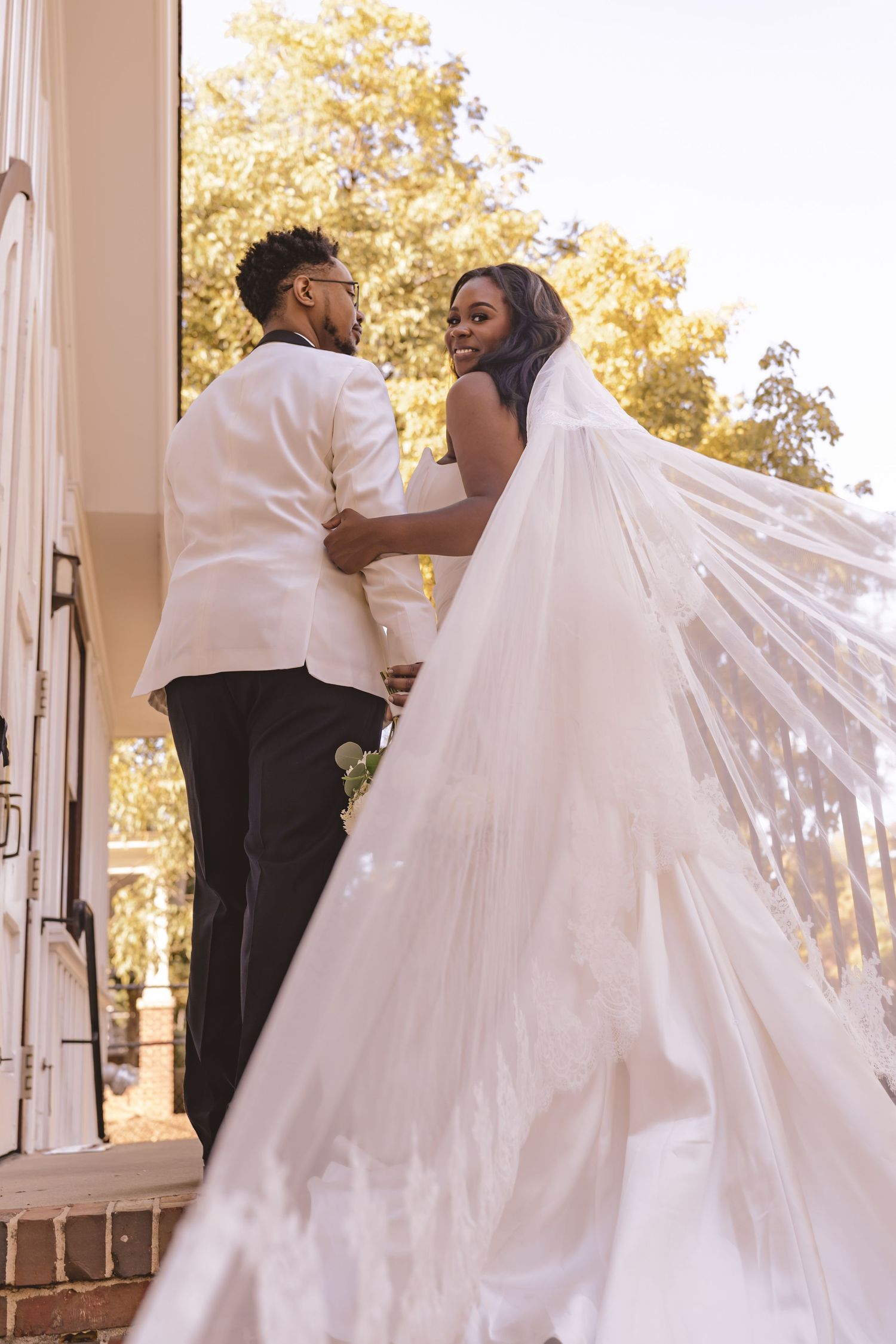Bride and groom with flowing veil outside at All Saints Chapel in Raleigh, NC