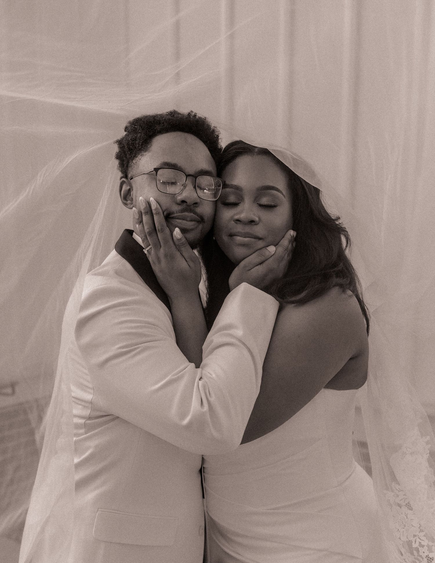 Bride and groom embracing under sheer fabric at All Saints Chapel in Raleigh, NC