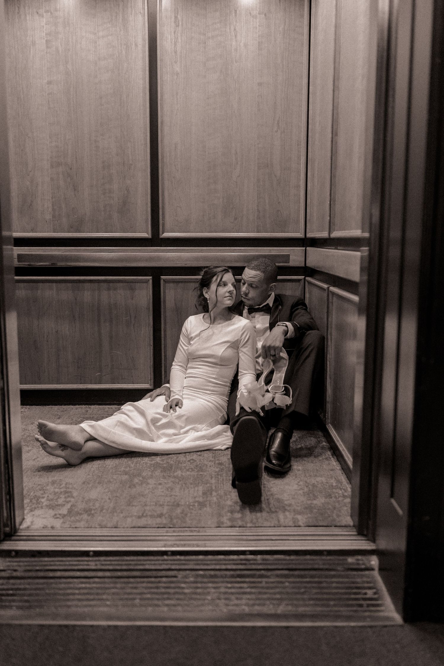 Bride and groom sitting on the floor inside an elevator at the Grove Arcade in Asheville, NC