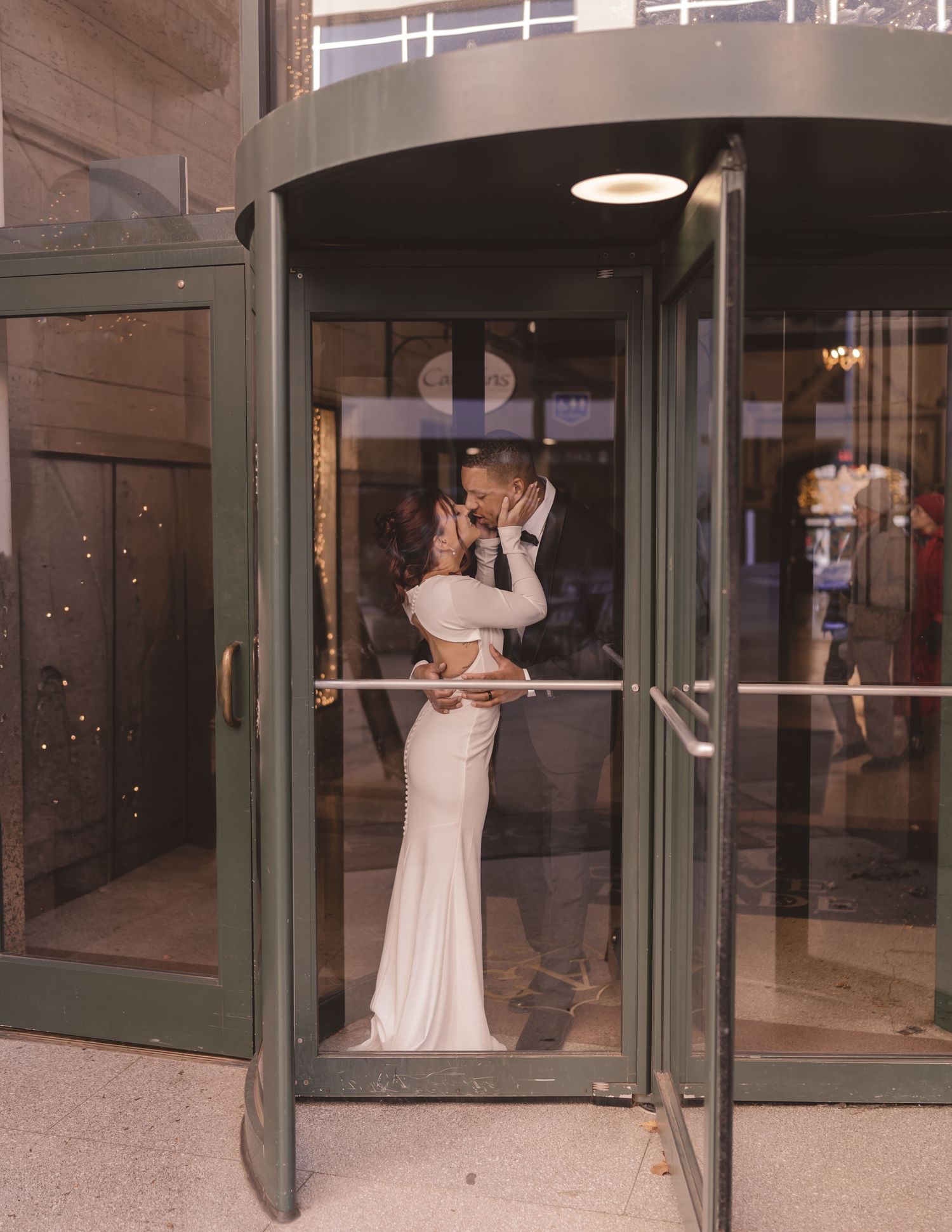 Bride and groom kissing in a revolving door at Grove Arcade in Asheville, NC