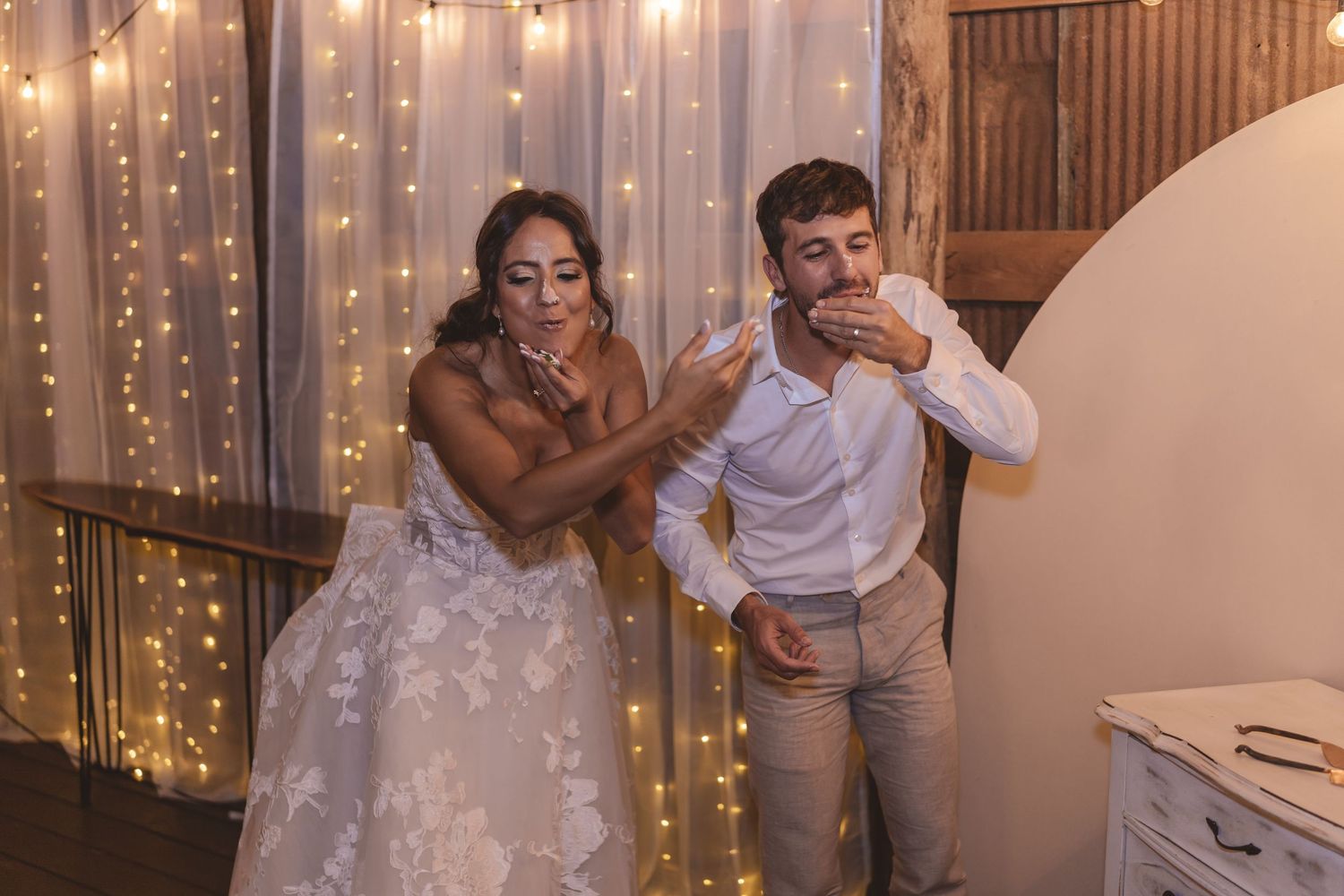 Bride and groom smashing cake in each other's faces during reception at Farmhouse Siloam in Mount Airy, NC