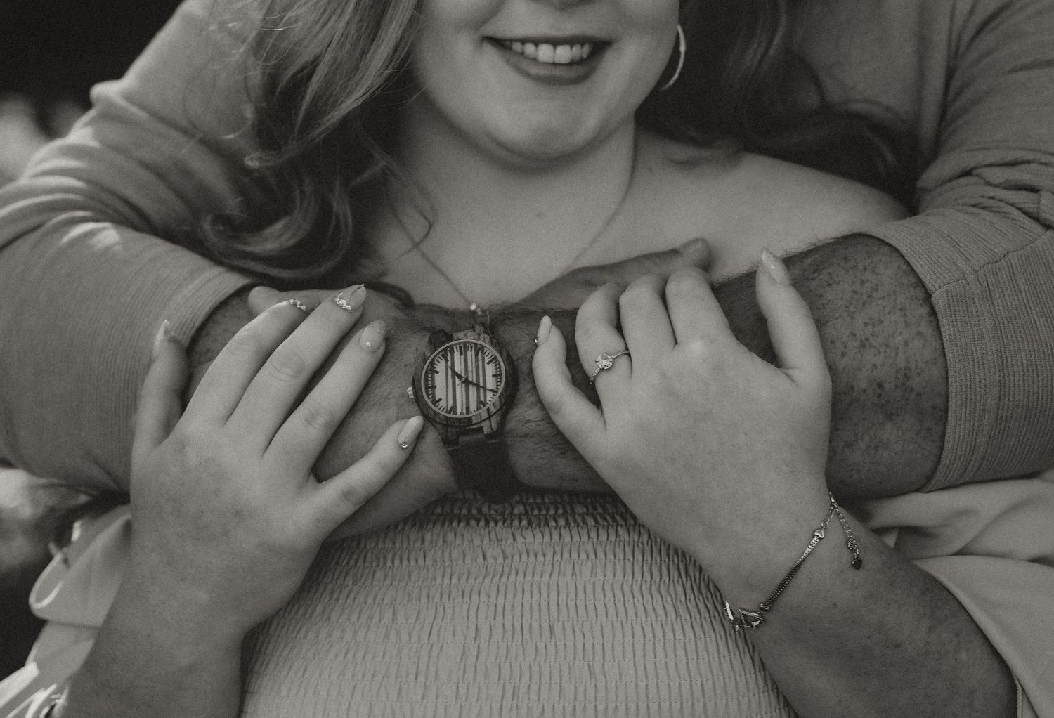 Close-up black and white photo of hands holding a monogrammed pendant.