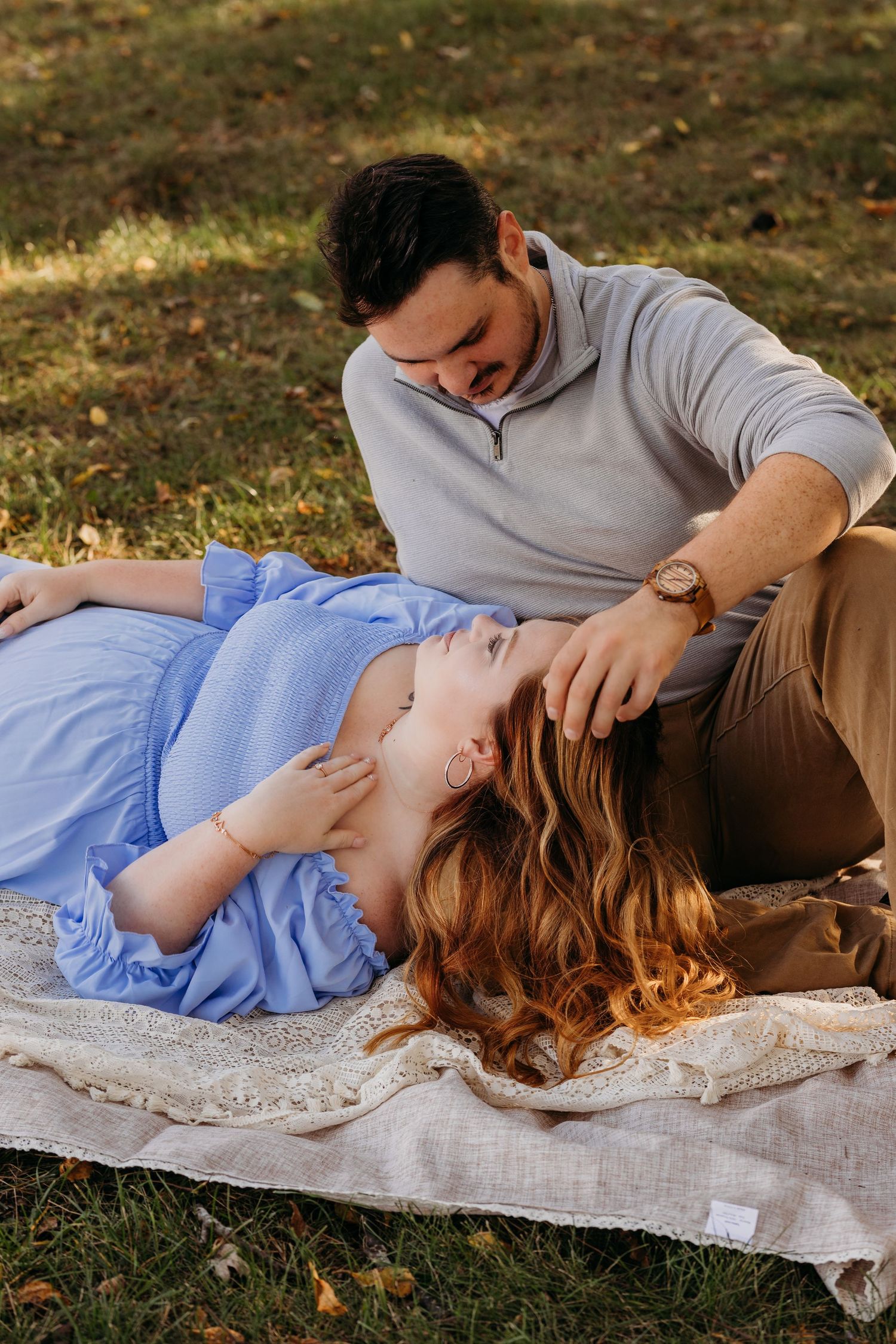 Couple relaxing on blanket during outdoor autumn photoshoot.