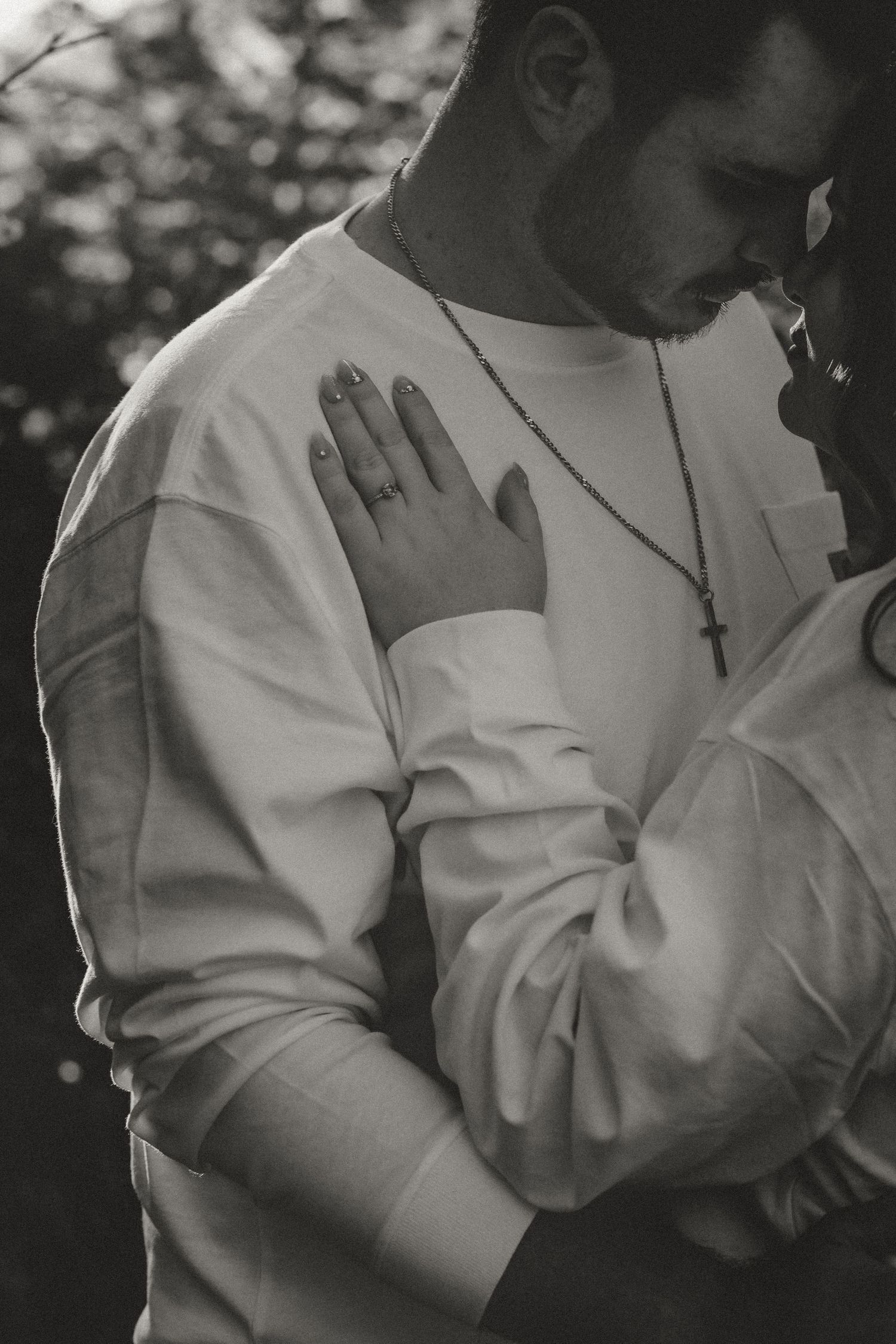 An intimate black and white portrait of a couple in white embracing with soft lighting.
