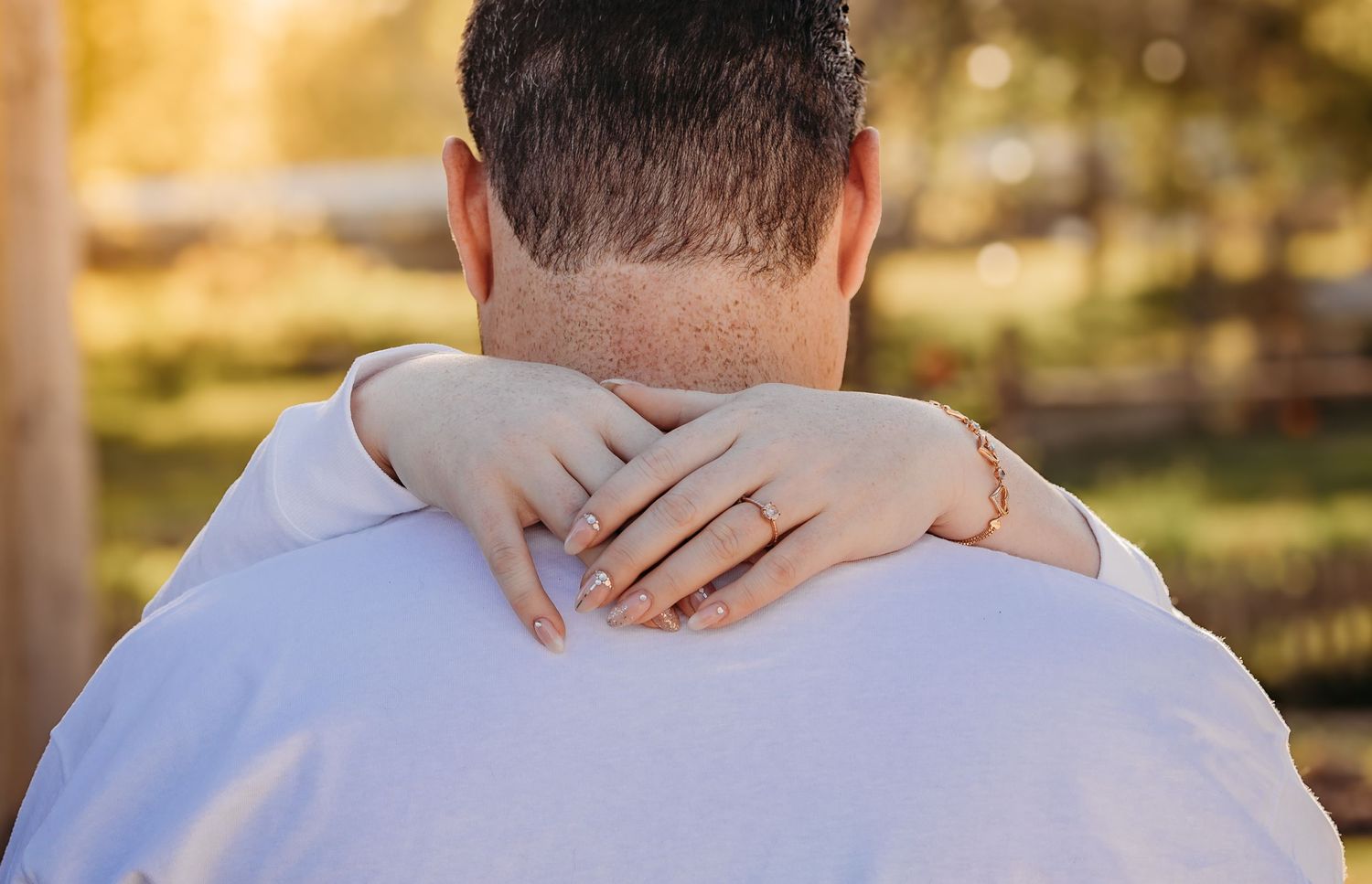 Close-up detail shot showing hands embracing during outdoor photo session.