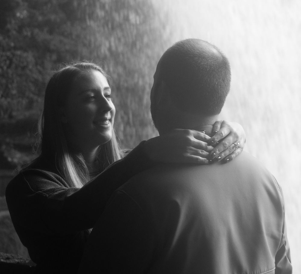 A black and white intimate portrait of two people sharing a tender moment in soft lighting.