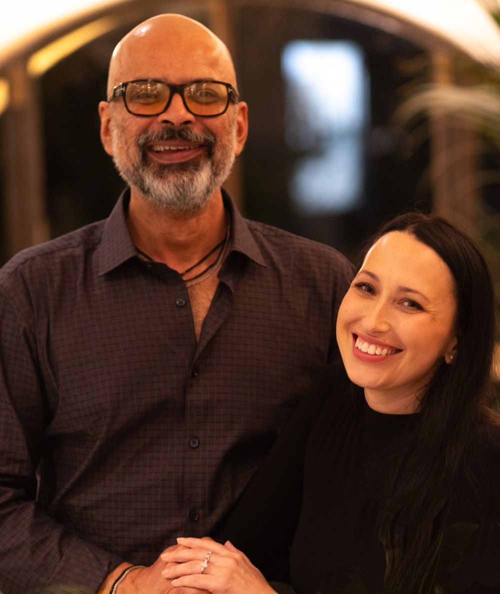 A happy couple smiles warmly at each other during a romantic dinner date.