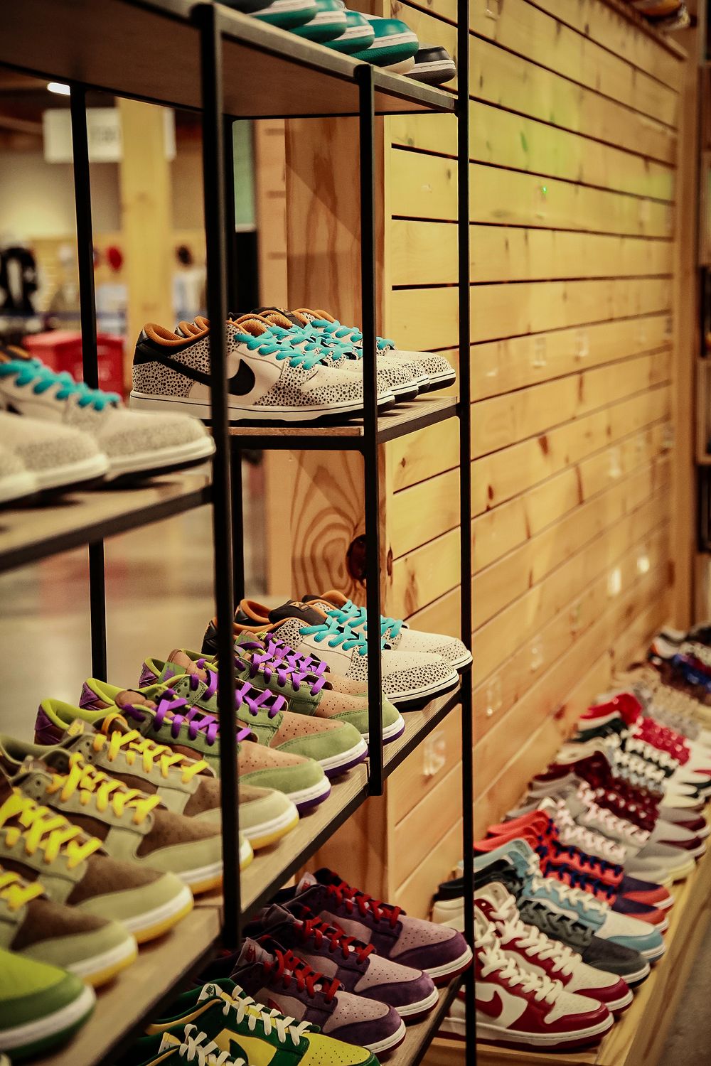 Colorful sneakers and athletic shoes displayed on wooden shelves at a retail store with wood paneled wall.