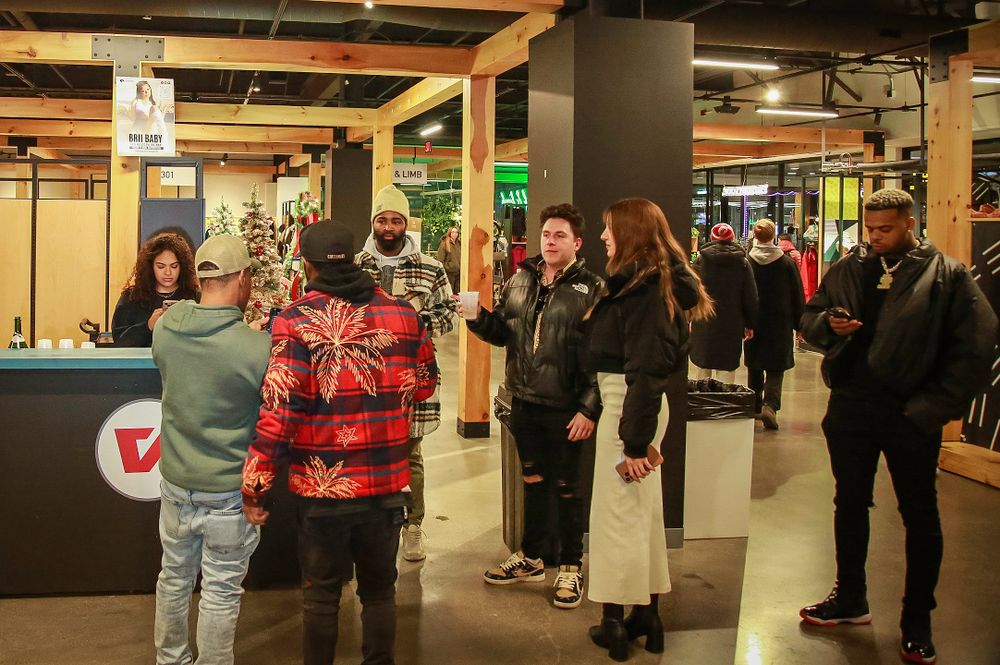 A crowded group of people waiting near a subway station entrance with displays and standing barriers.
