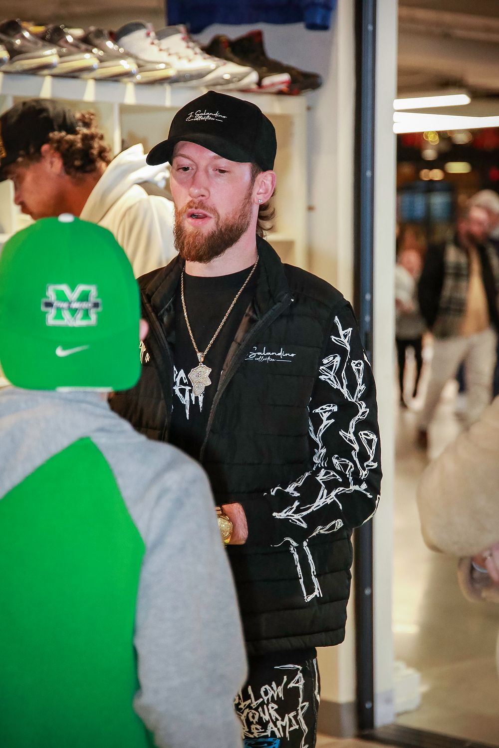 Person wearing black jacket and Nike baseball cap inside clothing store.