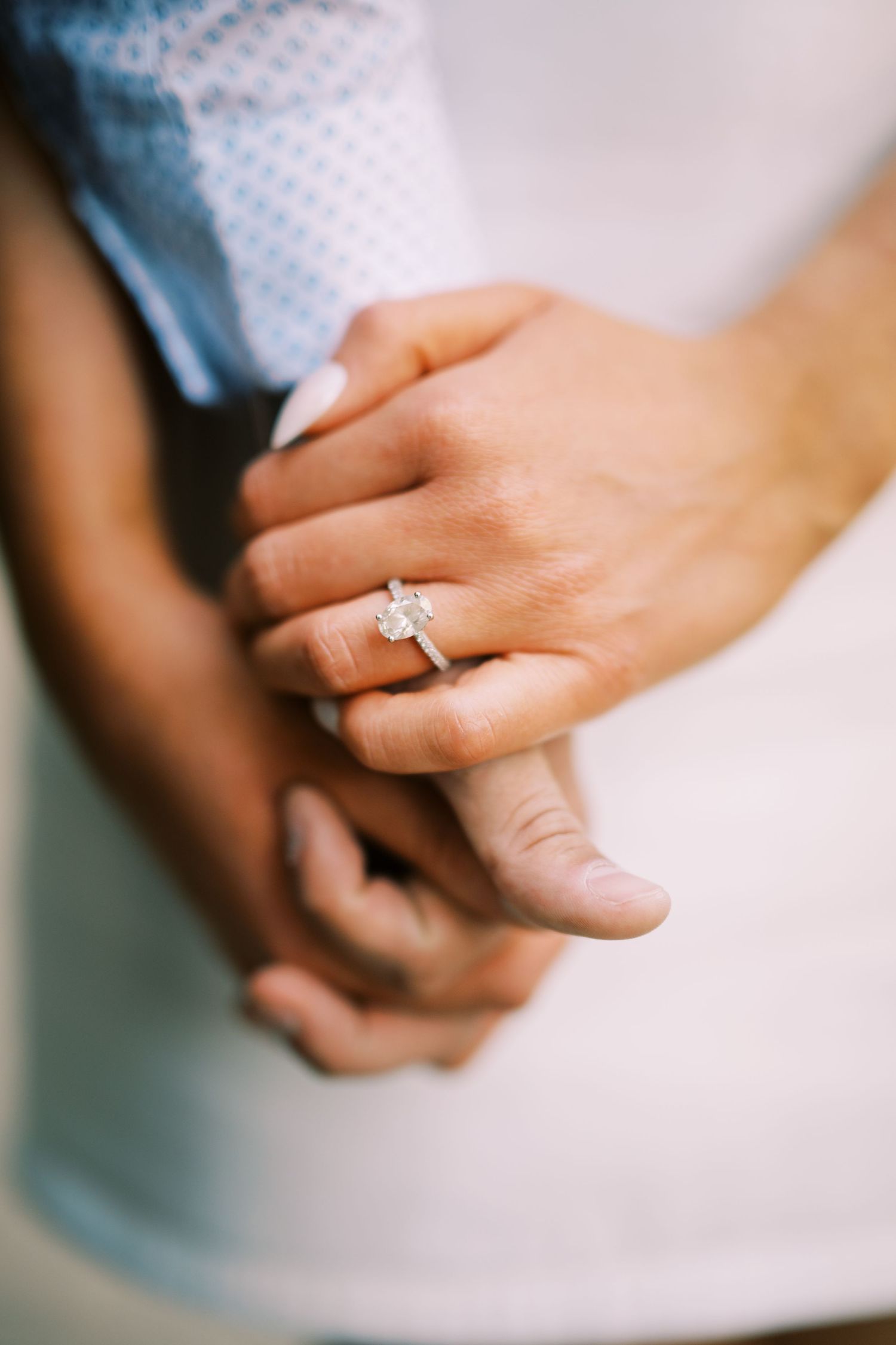 A close-up view of hands showing off a sparkling diamond engagement ring.