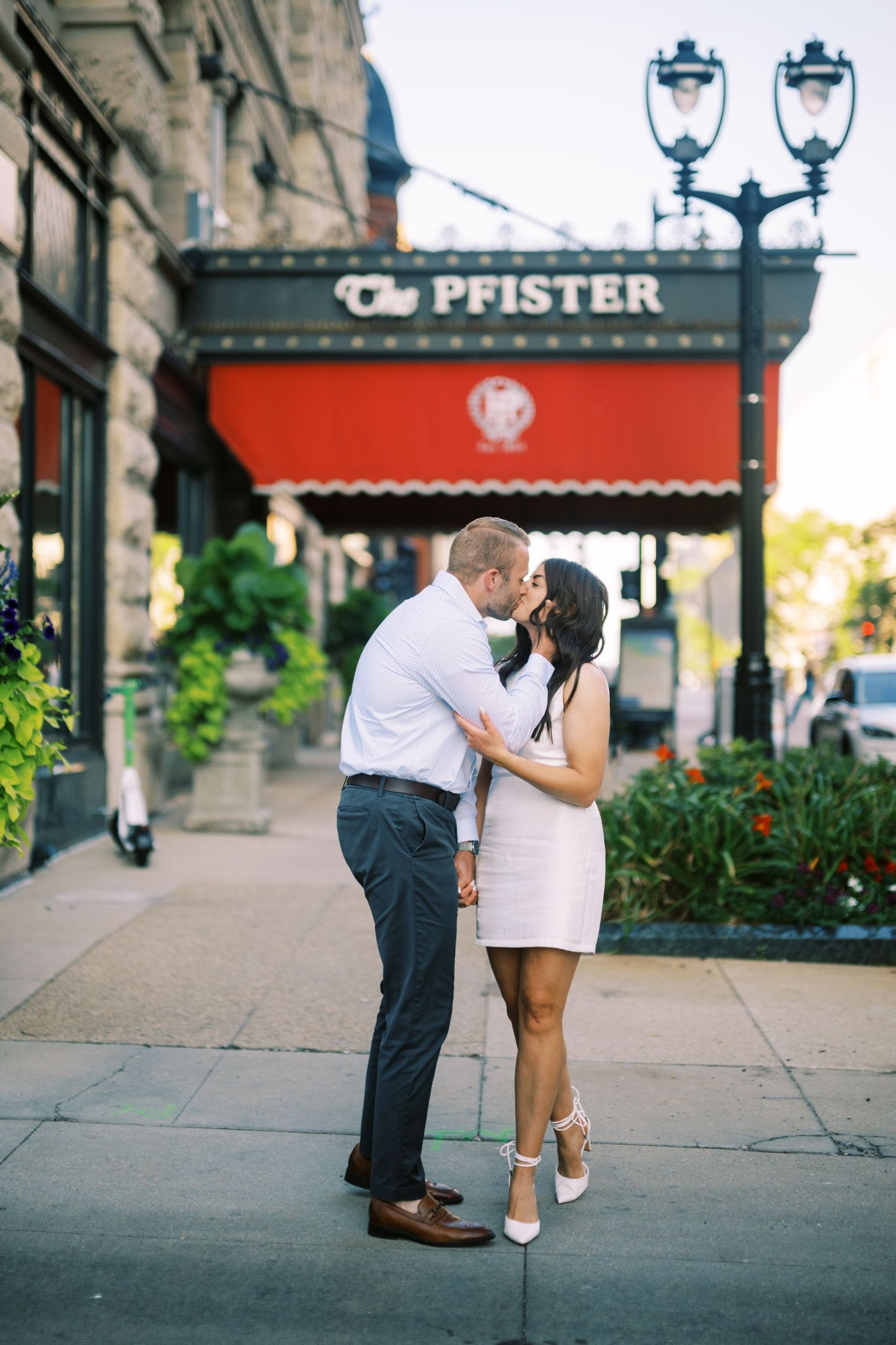 A couple shares a romantic moment on a city sidewalk outside the Pfister hotel in Milwaukee.