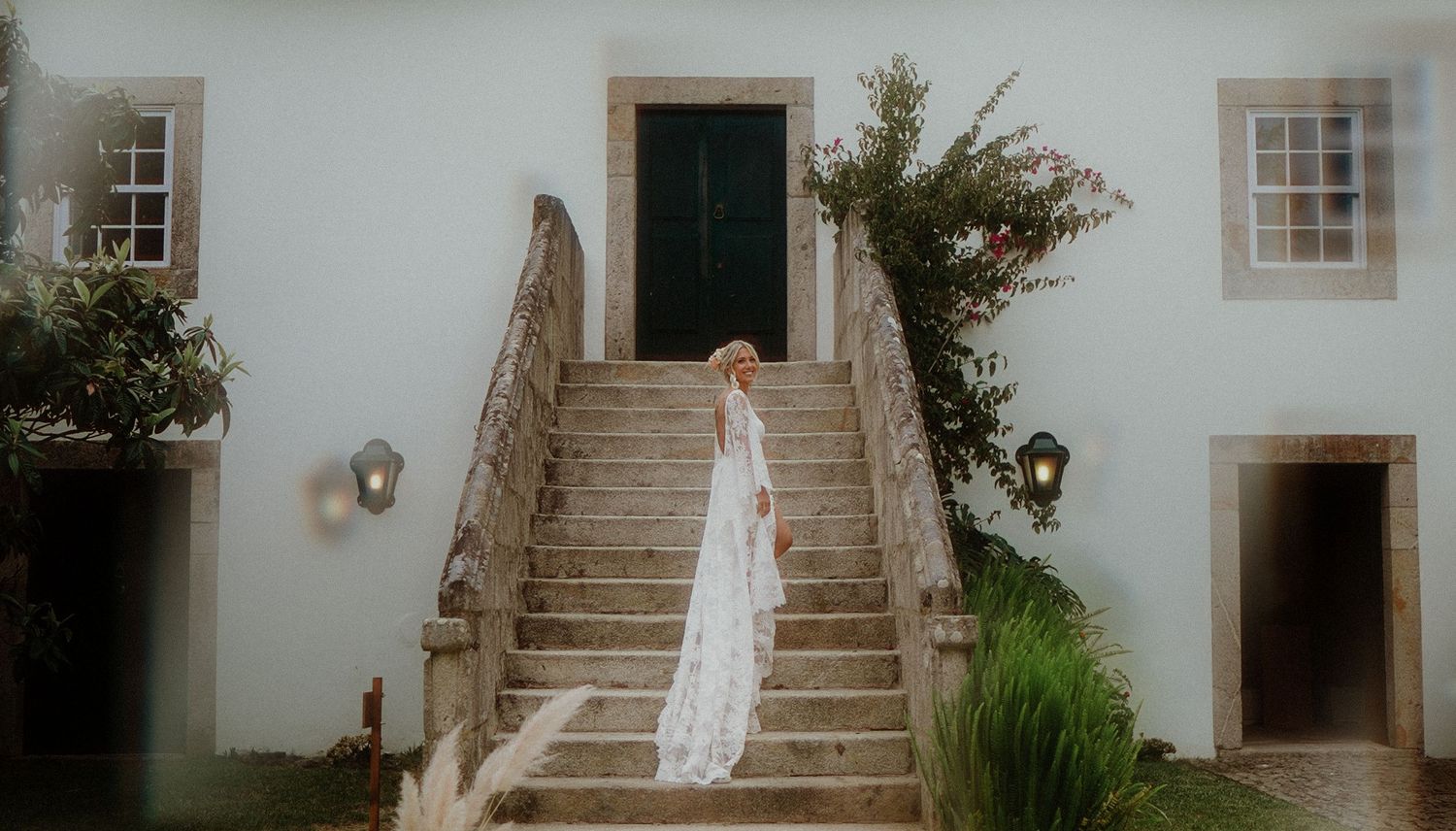 White wedding dress on display at elegant stone staircase entrance of historic building.