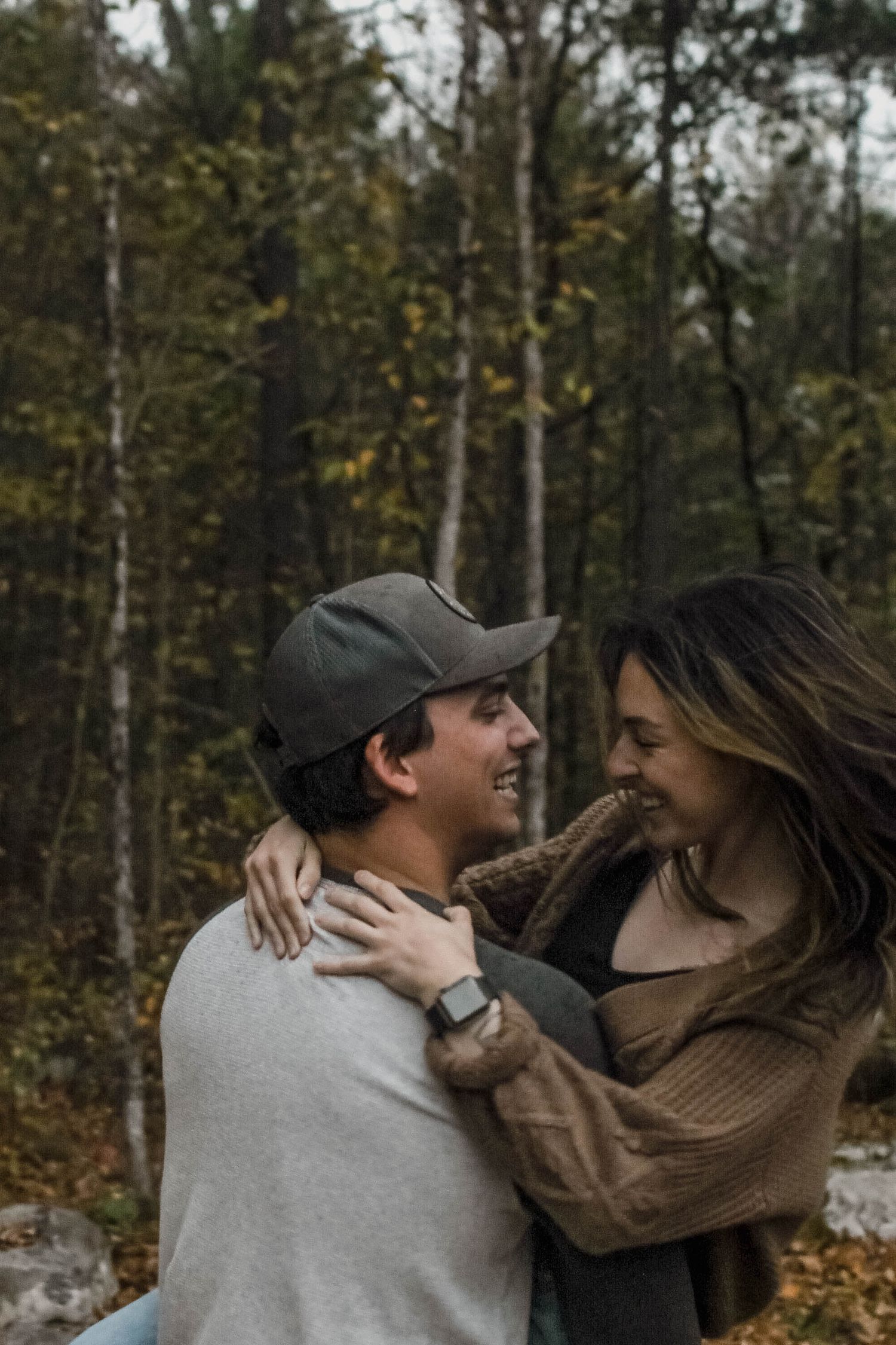 A couple shares an intimate moment while embracing in an autumn forest setting.