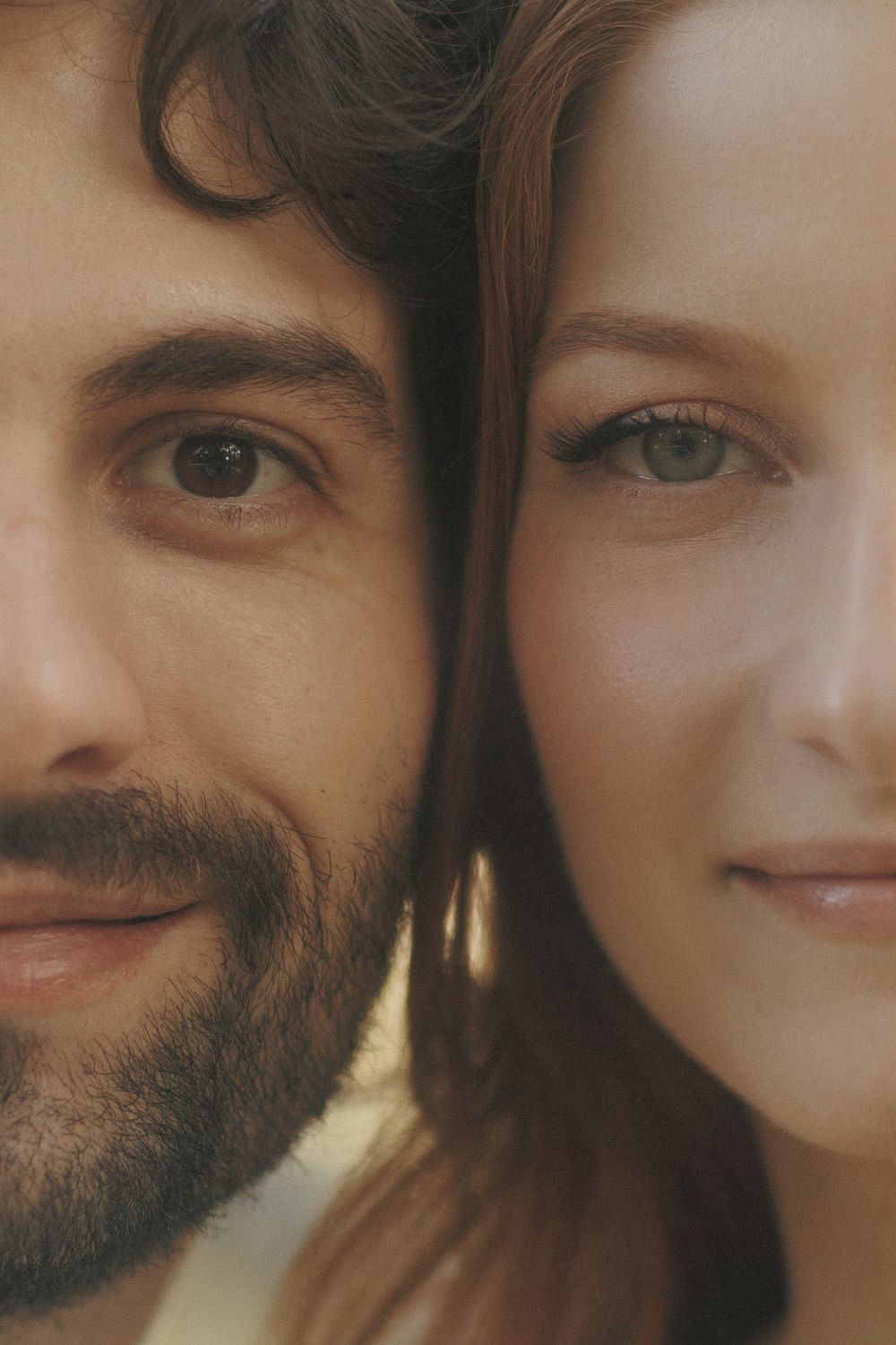 A close-up portrait showing two faces side by side in warm lighting.