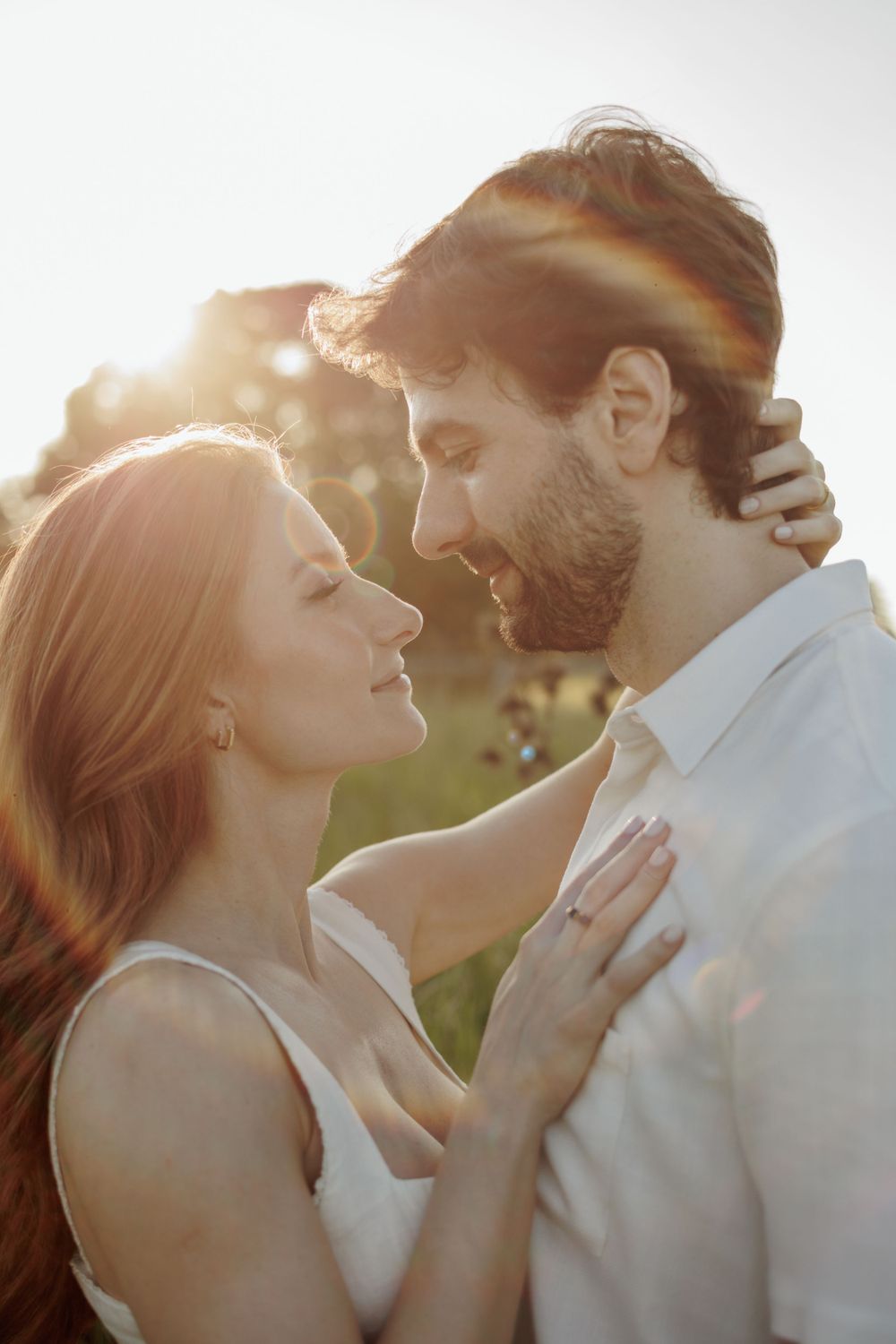 Romantic golden hour portrait of couple embracing outdoors.