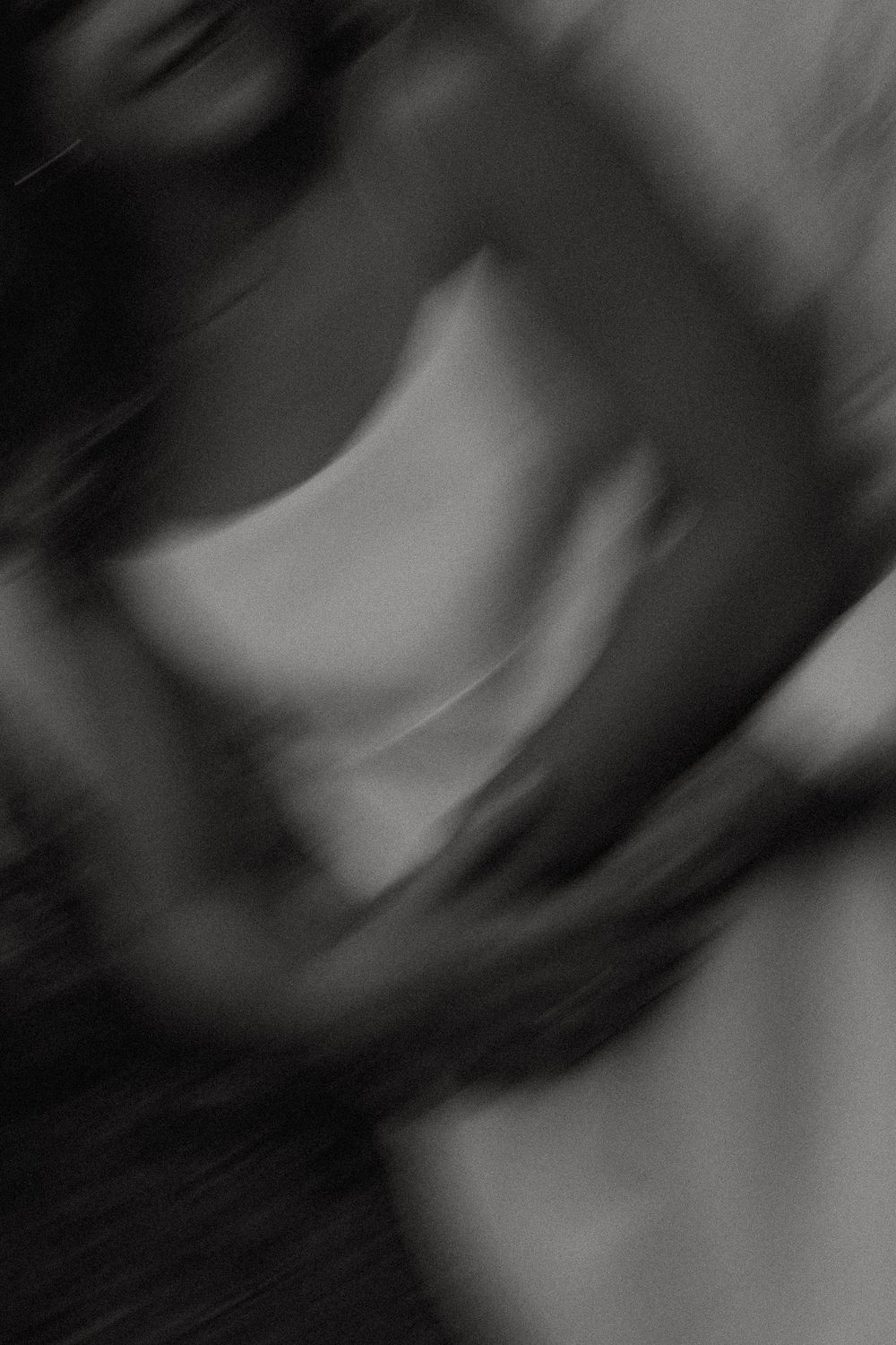 Abstract black and white blurred pattern creates a swirling motion effect in dark tones.