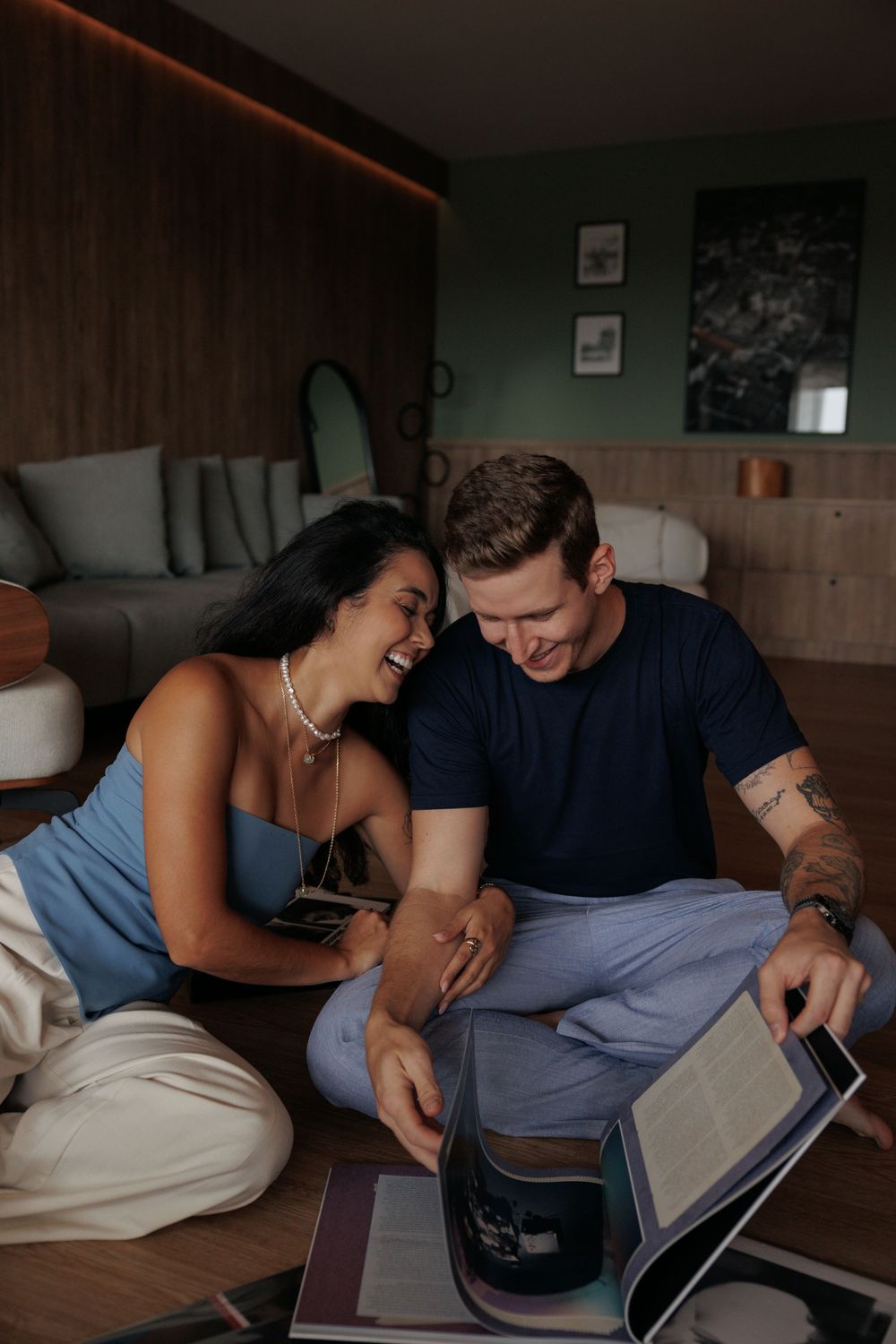 A couple shares an intimate moment while looking at a digital tablet together on a couch.