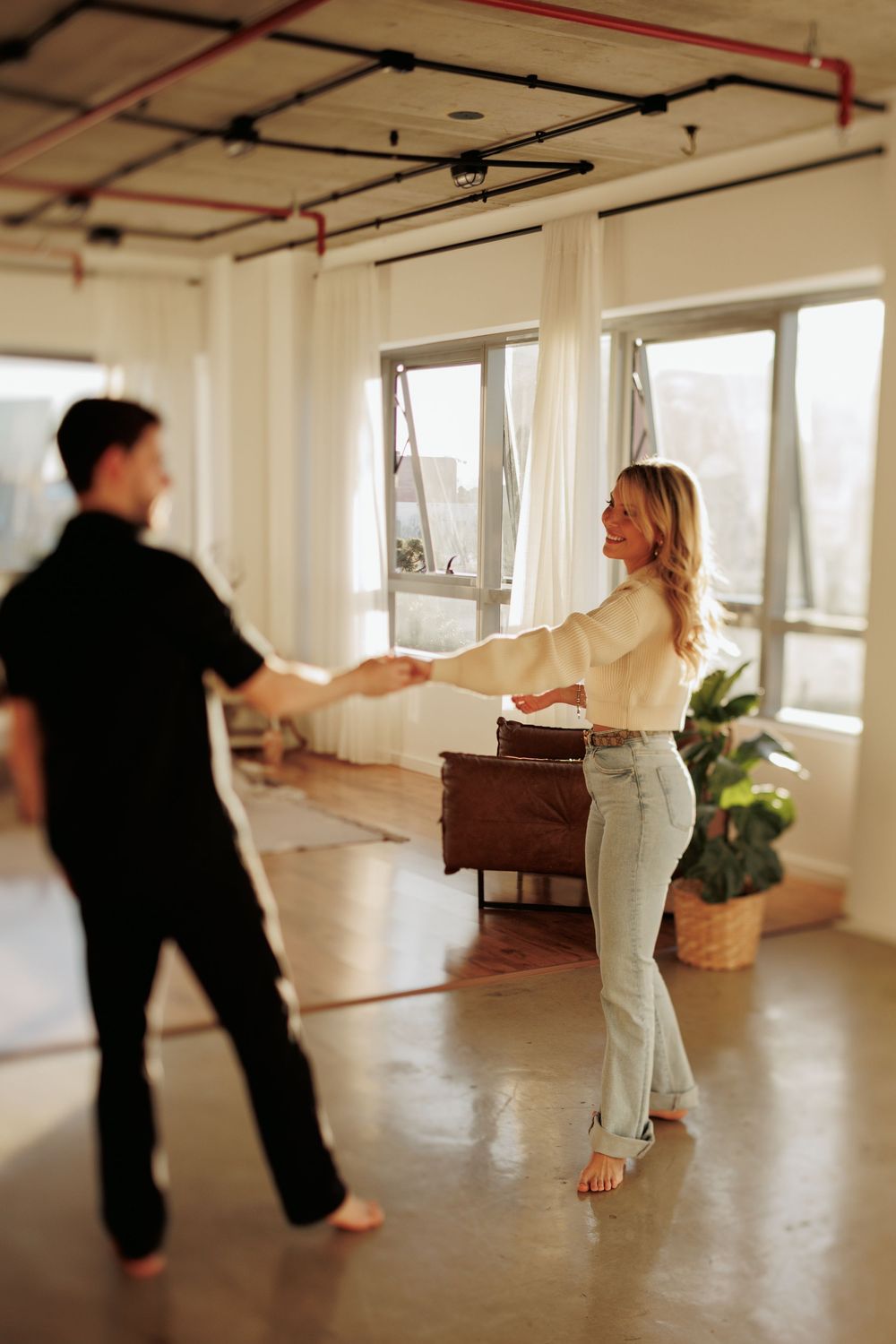 A sequence of dance movements captured in a bright studio space with exposed ceiling and wooden floors.