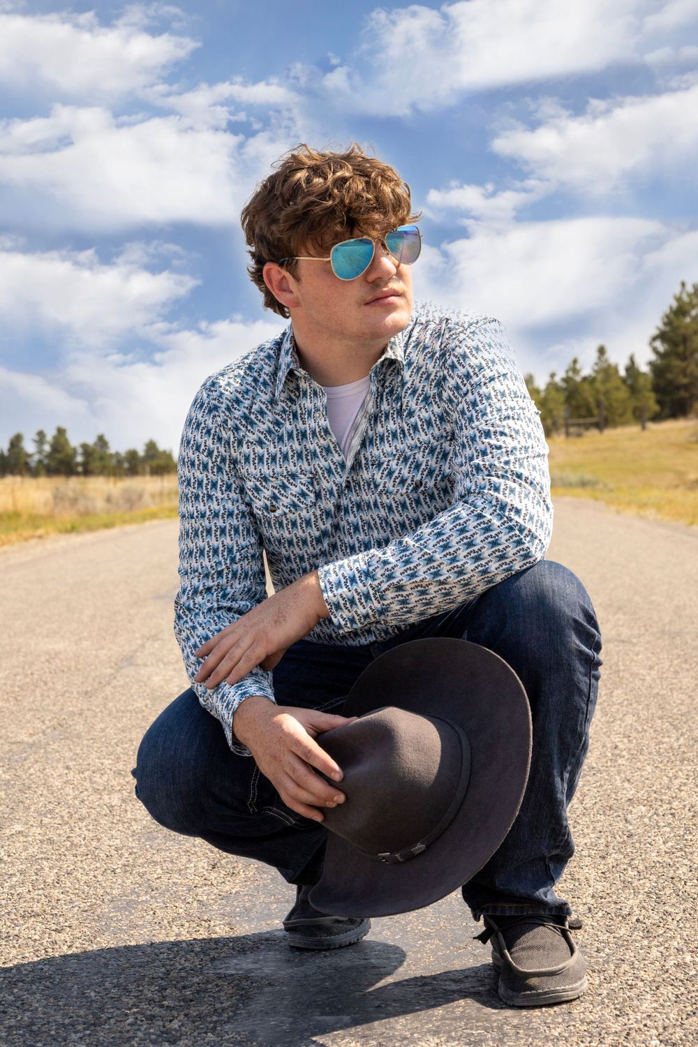 Senior boy poses outside with hat and sunglasses.