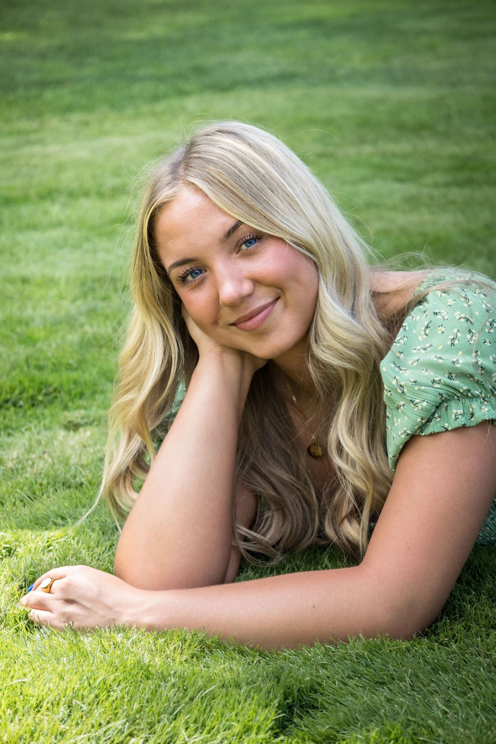 Senior poses outdoor during the spring soaking up the sun wile laying in the grass.