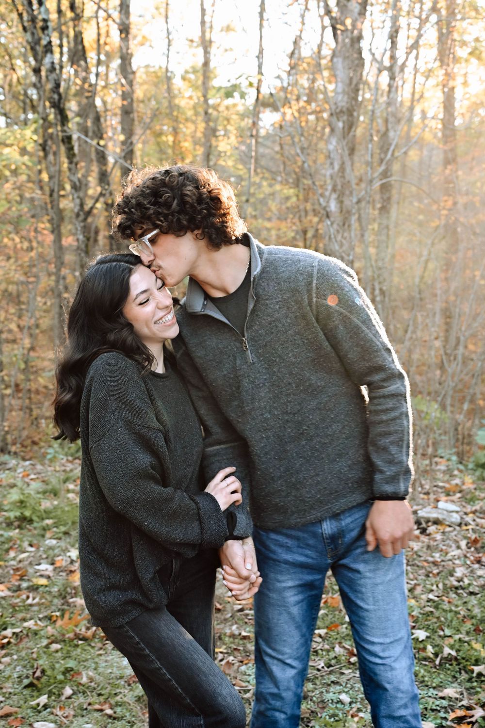 A sweet couple shares an intimate moment together during autumn in the woods while wearing cozy sweaters.