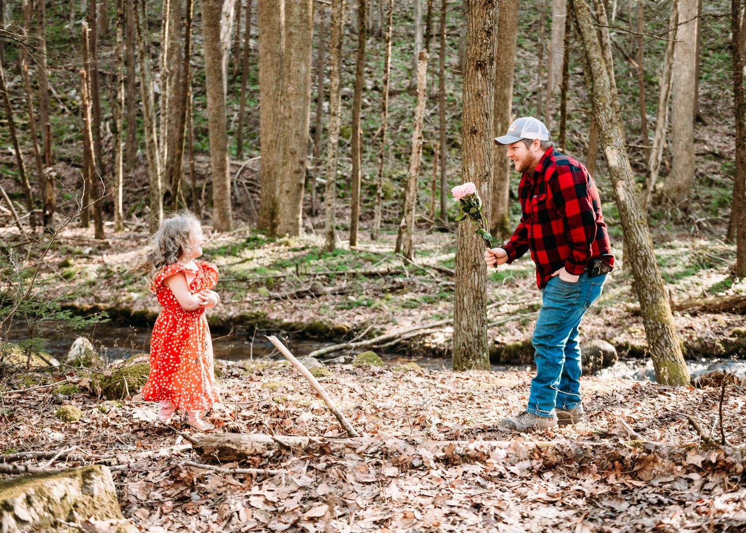 A heartwarming forest scene with red plaid and red dress creating a special moment among the trees.