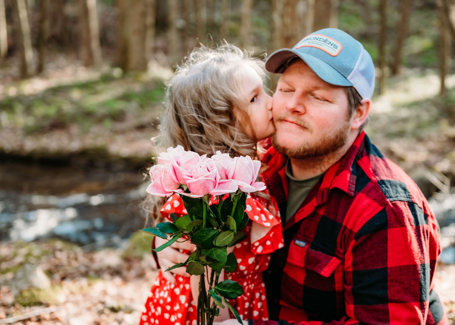 A touching forest scene with pink roses and buffalo plaid creating a heartwarming moment. Father and daughter