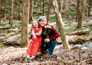 A tender forest portrait with red plaid and polka dots against natural woodland scenery.