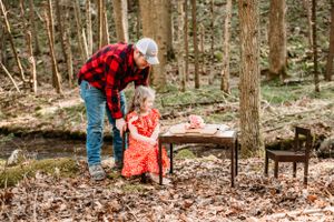 An outdoor tea party scene with rustic wooden furniture in a serene forest setting.