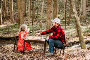 A sweet tea party moment in the woods with red plaid and polka dot dress against natural scenery.