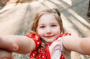 A close-up selfie-style photo outdoors featuring a bright red polka dot dress.