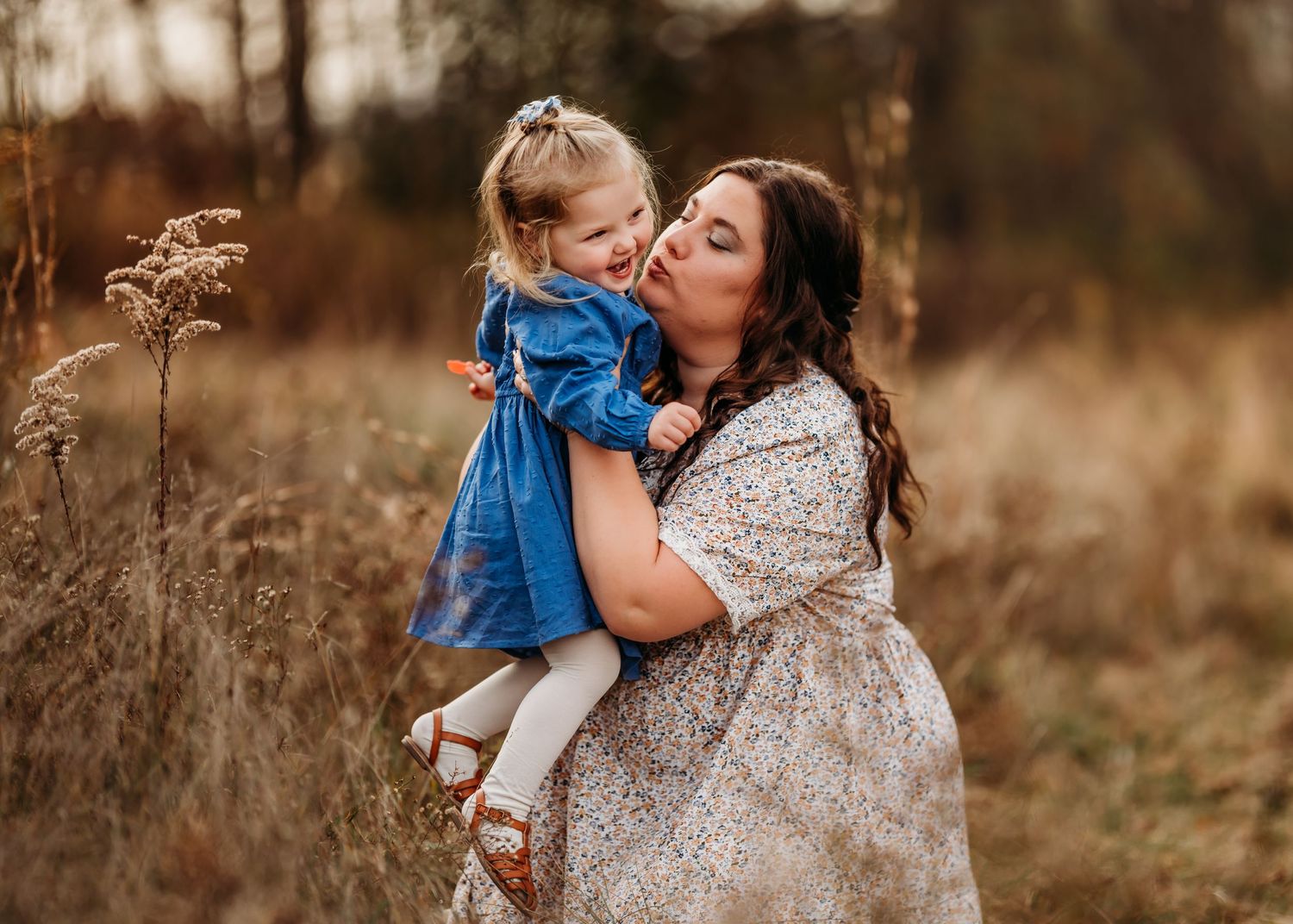 A heartwarming outdoor portrait in a rustic field during golden hour with dried grasses and soft autumn lighting.