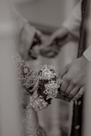 Close-up black and white shot of hands holding intricate beaded wedding details.