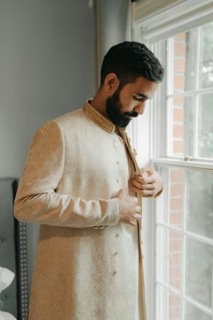 Elegant cream-colored traditional sherwani with detailed embroidery and high collar.