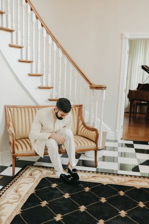 Traditional formal attire preparation moment on a striped carpet by a staircase.