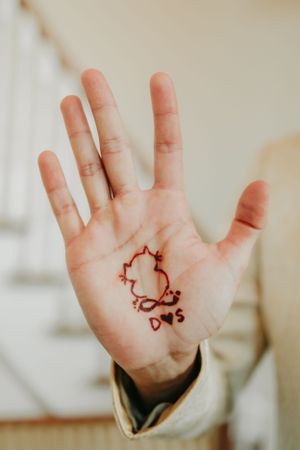 Palm showing hand-drawn heart with initials D&S in temporary henna design.