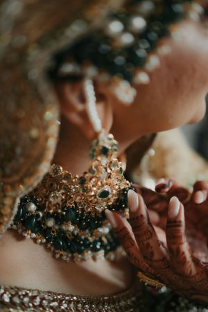 Close-up of intricate bridal jewelry with emerald and pearl details.