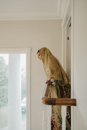 Ornate gold and cream traditional bridal dress photographed by a window.