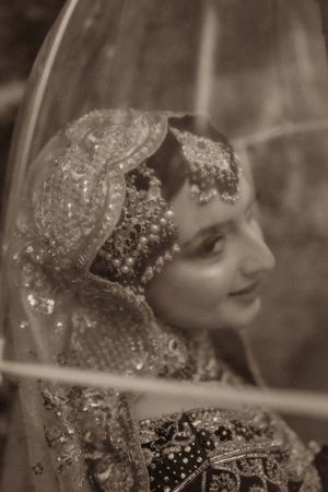 Vintage-style portrait of bride in traditional South Asian wedding attire with detailed headpiece.